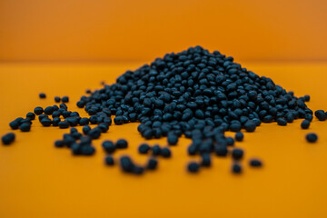 Black granules on an orange background - obrazy, fototapety, plakaty