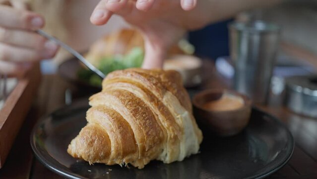 A girl takes the croissant filling from her boyfriend, Croissant with cheese and herbs. close-up, Slow motion. woman eats a delicious Sandwich croissant
