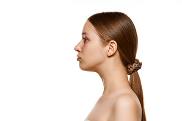 Profile view portrait of beautiful young woman with bare shoulders, well-kept spotless skin...