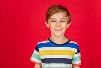Happy young boy on isolated red background. Closeup portrait of adorable happy little boy smiling. Little funny blond boys isolated on red background. Portrait of happy joyful beautiful little boy