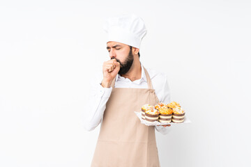 Young man holding muffin cake over isolated white background is suffering with cough and feeling bad