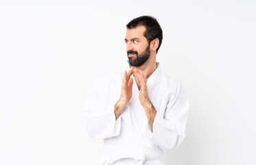 Young man doing karate over isolated white background scheming something