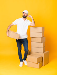Full-length shot of delivery man among boxes over isolated yellow background making the gesture of...