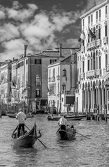 Two gondoliers cross the famous Grand Canal in Venice, Italy, in black and white - obrazy, fototapety, plakaty