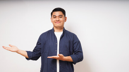 Young Asian man smiling when looking and pointing to the right side on white background. studio shot