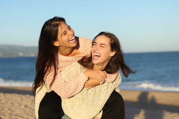 Two joyful friends joking and laughing on the beach