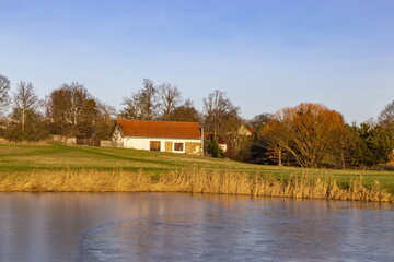 Fototapeta na wymiar House on a pond bank. Snowless winter in central Europe.