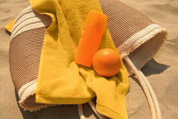 Beach bag, sunscreen and other accessories on sand