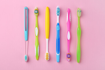 Many different toothbrushes on pink background, flat lay