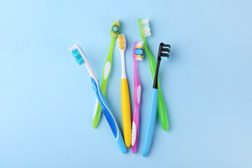 Many different toothbrushes on light blue background, flat lay