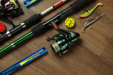 Spinning rods and fishing tackle on wooden background, flat lay