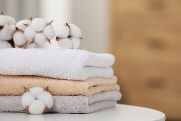 Terry towels and cotton branch with fluffy flowers on white table indoors, closeup. Space for text