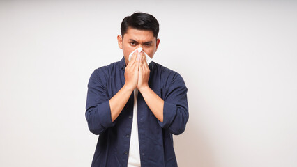 Young Adult Asian man cover his nose and mouth with tissue when sneezing on white background. studio shot