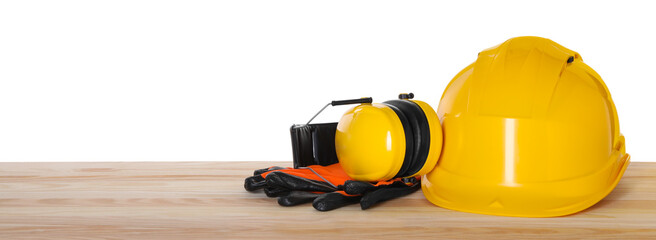 Hard hat, earmuffs and gloves on wooden table against white background. Safety equipment