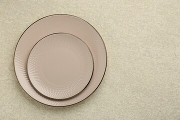 Beautiful ceramic plates on beige table, top view. Space for text