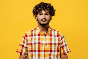 Young serious calm attractive brunet Indian man with curly hair, mustache he wears shirt casual clothes looking camera isolated on plain yellow color wall background studio portrait Lifestyle concept