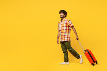 Full body traveler Indian man wear shirt casual clothes hold suitcase isolated on plain yellow...