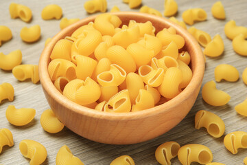 Raw macaroni pasta on wooden table, closeup
