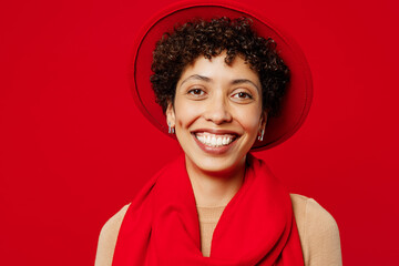 Close up young smiling happy satisfied fun cool woman of African American ethnicity she wears beige sweater hat scarf looking camera isolated on plain red background studio portrait Lifestyle concept