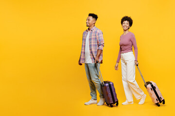 Traveler couple two friend family man woman wearing casual clothes hold suitcase bag go isolated on plain yellow background. Tourist travel abroad in free time rest getaway. Air flight trip concept. - obrazy, fototapety, plakaty