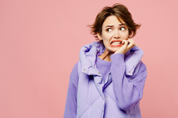 Young sad mistaken doubtful woman she wearing purple vest sweatshirt casual clothes look aside biting nails fingers isolated on plain pastel light pink background studio portrait. Lifestyle concept. - obrazy, fototapety, plakaty