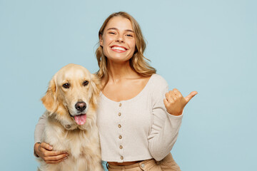 Young owner woman with her best friend retriever dog wear casual clothes point finger aside on area...