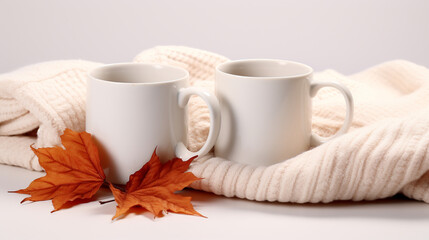 Obraz na płótnie Canvas two empty white coffee mugs mockup decorated with a woolen scarf and autumn maple leaves