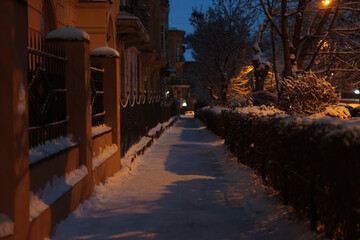 Picturesque view of city street covered with snow in evening