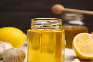 Jar with honey, garlic and lemons on table, closeup