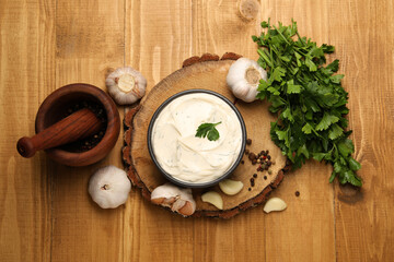 Tasty sauce with garlic, spices and parsley on wooden table, flat lay