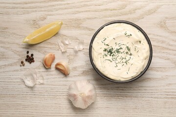 Tasty sauce with garlic, spices, lemon and dill on light wooden table, flat lay