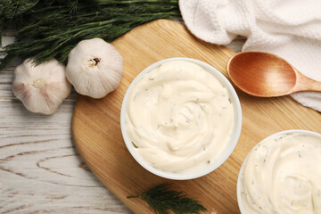 Tasty sauce with garlic, dill and spoon on light wooden table, top view