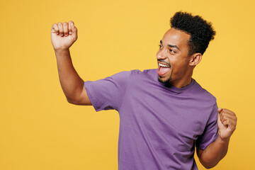 Young fun man of African American ethnicity wear purple t-shirt casual clothes doing winner gesture...