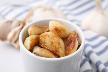 Fried garlic cloves in bowl on table, closeup