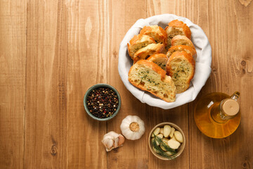 Tasty baguette with garlic, oil and other spices on wooden table, flat lay. Space for text