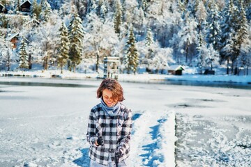 Girl play with snow by the lake in front of mountains