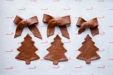 Raw gingerbreads in form of Christmas tree and festive bow ready for baking