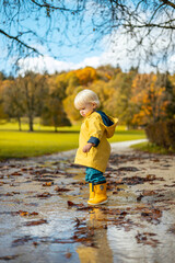 Sun always shines after the rain. Small bond infant boy wearing yellow rubber boots and yellow...