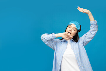 Naklejka premium Young woman in a sleeping mask on a blue background