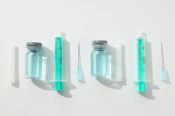 Glass medical bottles with vaccine and syringes on white background, top view
