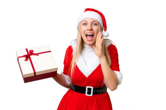 Young blonde woman with christmas hat and holding a gift over isolated chroma key background shouting with mouth wide open