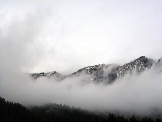Fog is creeping over the mountain range. A picturesque panorama of wild nature