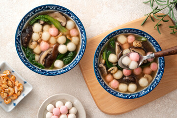 Eating homemade red and white small tangyuan with savory soup and vegetable.