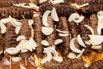 Grilled meat on wooden skewers sprinkled with onions close-up. Lula - kebab.