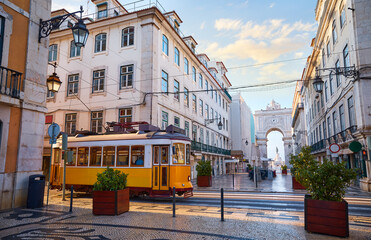 Lisbon, Portugal. Yellow touristic retro tram. Triumphal Arch of Rua Augusta near Praca do Comercio (Commercial Square. Sunny day in famous tourist place Lisboa