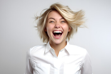 Portrait of a happy young blonde woman in a white shirt on a gray background - obrazy, fototapety, plakaty