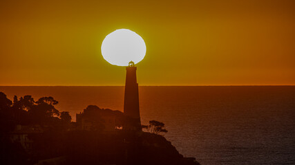 Fototapeta premium Coucher de soleil en bord de mer sur le phare de la presqu'île du Cap Ferrat depuis le Cap de Nice