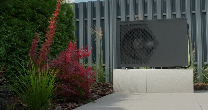 The heat pump for heating the pool is mounted on site. Ornamental plants nearby. Energy Saving Technologies