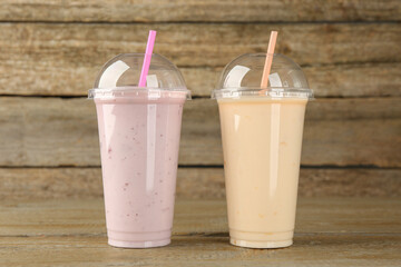 Plastic cups with different tasty smoothies on wooden table