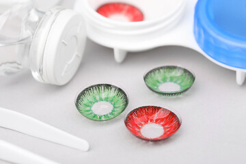 Different color contact lenses and tweezers on white background, closeup